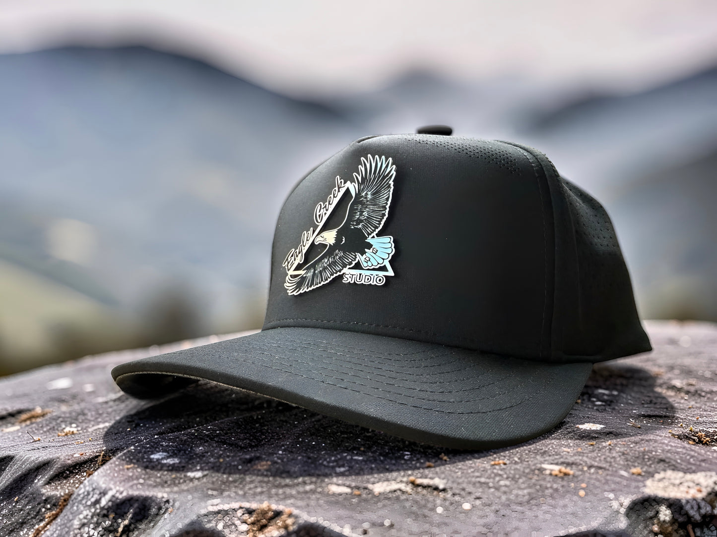 Premium Black cap with Eagle Creek Studio Elevation Design on a textured surface